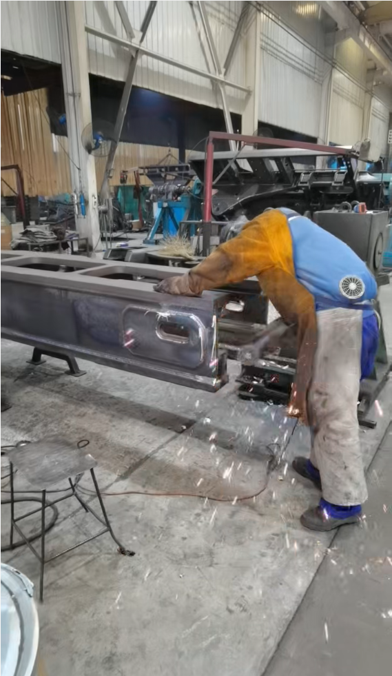 Experienced welders perform precision welding on heavy machinery frames in the production workshop.